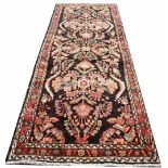 An Iranian wool runner, worked with a bold floral design against a black ground,