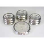 A glass and silver mounted bottle coaster 14cm diameter and eight smaller examples 10cm diameter,