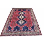 A Caucasian hand woven wool rug, worked with three medallions against a red ground,
