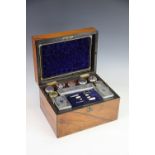 A Victorian walnut fitted dressing case, the interior enclosing assorted dressing table jars,