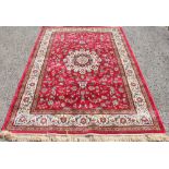 A Kashmir rug, worked with an all over medallion foliate design against a red ground,