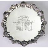 A silver waiter, Barker Brothers, Chester 1908, the shell cast rim, raised on three scroll feet,