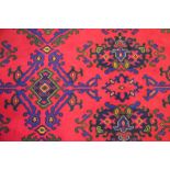 A wool carpet, worked with a foliate design against a red ground,