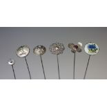 A collection of six hat pins, to include; a silver button mounted example,