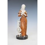 A 19th century South German carved ivory and carved softwood figure of a medieval maiden beside a