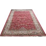 A Kashmir rug, worked with an all over floral design with animals, against a red ground,