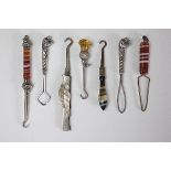 A selection of seven glove hooks, to include; three with banded agate handles,