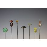 A collection of seven hat pins, to include; a carved jade example,