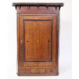 A George III inlaid oak hanging corner cabinet, with moulded cornice and base drawer,
