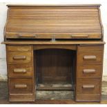An early 20th century light oak roll top desk, with tambour enclosing a fitted interior,