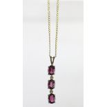 A rubellite set yellow gold pendant, designed as three oval stones in a vertical bar,
