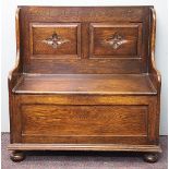 A 1920's oak settle of small proportions, the two panel back each carved with central floral motif,