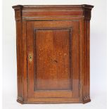 An oak and mahogany cross banded corner cupboard with a central inlaid bird crest,