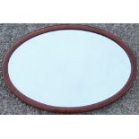 An Edwardian inlaid mahogany oval wall mirror, with bevelled plate,