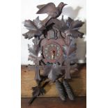 A stained pine carved cuckoo clock, with leaf decoration and bird surmount, with pendulum,