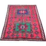 A Caucasian nomadic wool rug, worked with geometric motifs against a red ground,