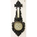 A carved black forest barometer and thermometer, the cased carved with blossoming rose,