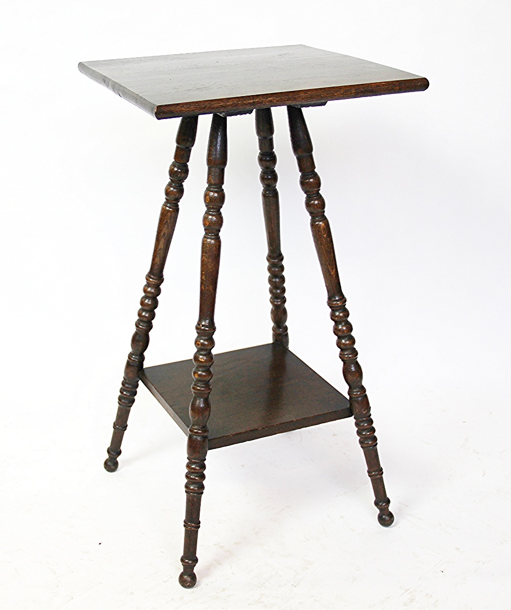 An Edwardian oak two tier occasional table, the square top on four turned legs,