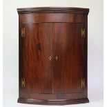 A George III mahogany bow front corner cupboard,