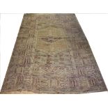 A Persian rug, worked with a geometric design in pale colours, worn,