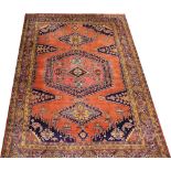 A Caucasian hand woven wool carpet, worked with geometric motifs against a red ground,