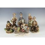 Five Capo Di Monte style figurines, to include a man and donkey pulling a barrel organ,