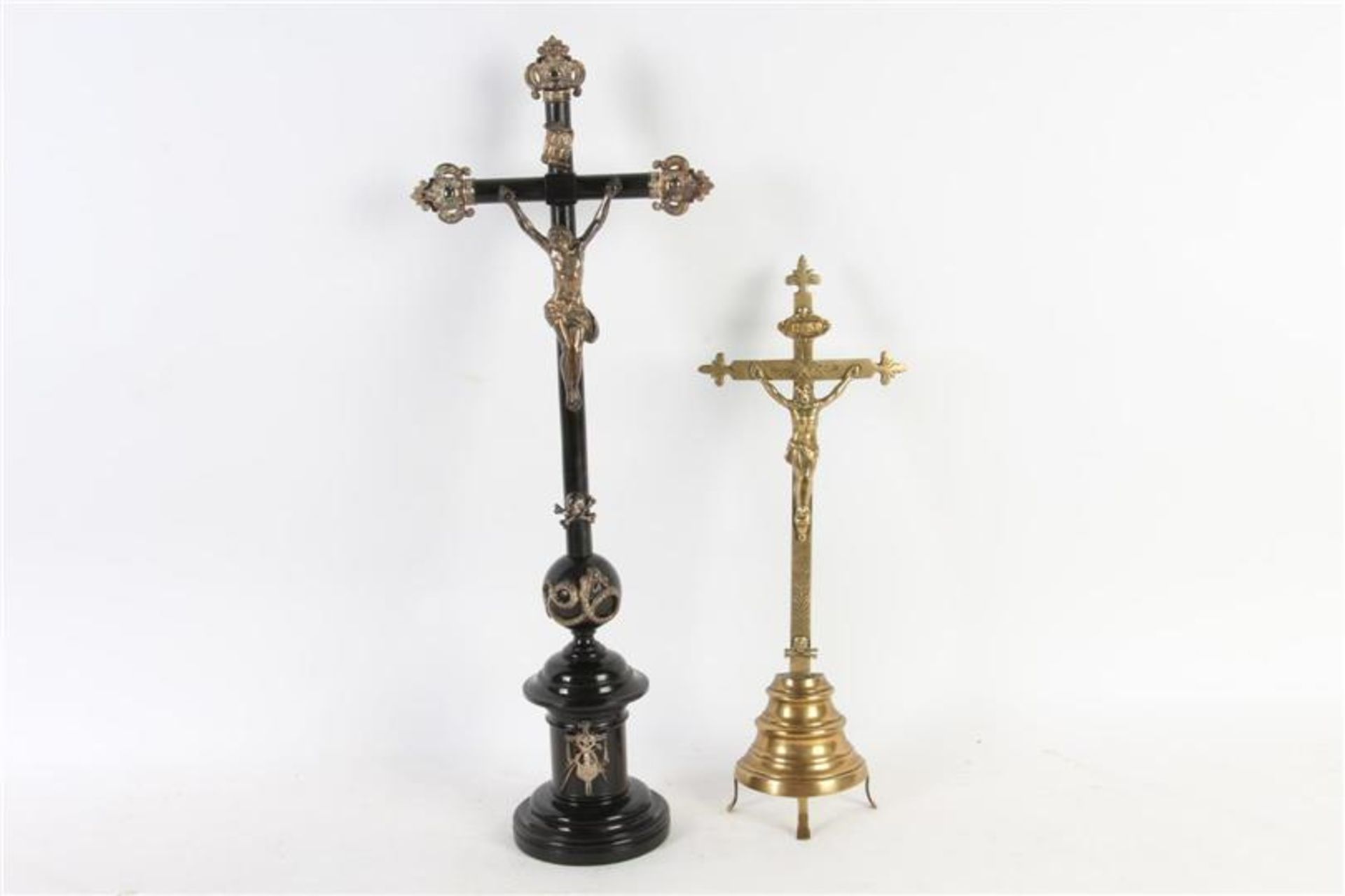 Gezwarte houten crucifix met zilveren beslag en een koperen crucifix.