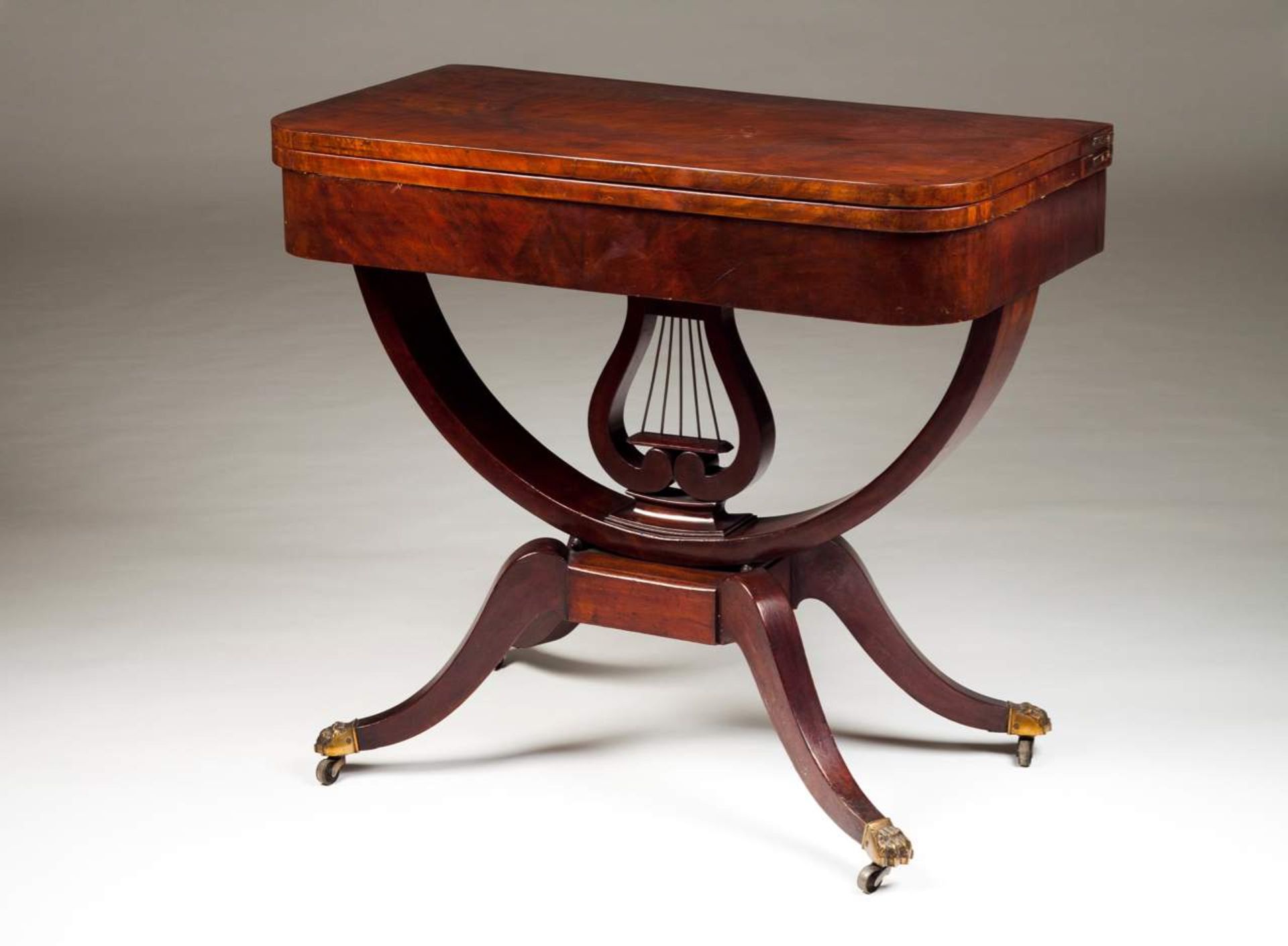 A pair of Empire style card tables Mahogany and burr-mahogany Four claw feet with castors Pierced