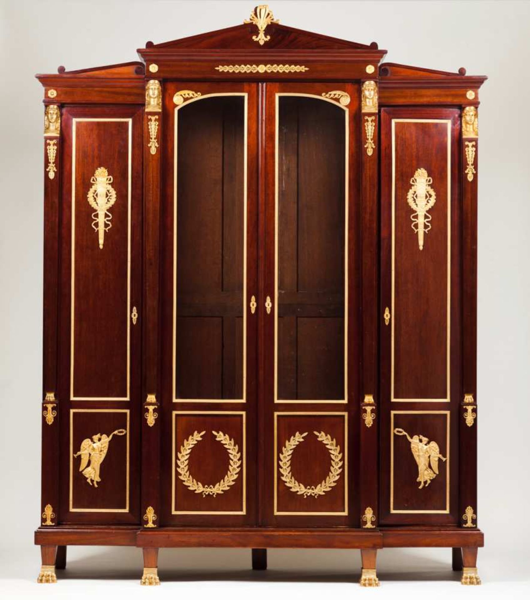 A library cabinet in the Empire style Mahogany with gilt bronze mounts representing masks, winged