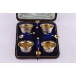 A silver condiment set by Jays, comprising of four embossed and engraved round salts and four