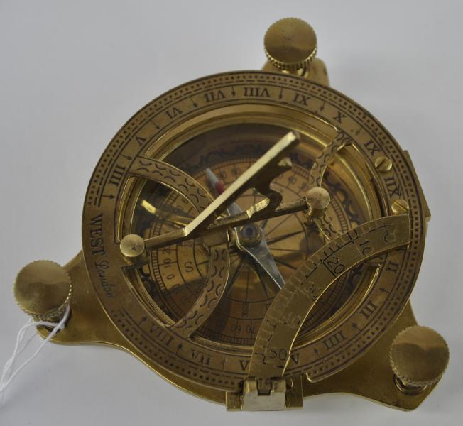 A brass combined compass and sun dial, with three adjustable feet, marked West, London, the dial 9cm