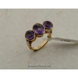 Three stone amethyst dress ring, rubover set in yellow metal stamped 9ct, ring size M