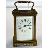 A brass carriage clock with white enamel dial and Roman numerals, signed Comber Woking.