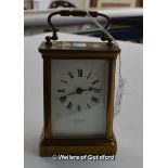 A brass carriage clock with white enamel dial and Roman numerals, signed Comber Woking.
