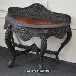 *An Anglo-Indian half moon hardwood table with carved gallery, four carved elephant head cabriole