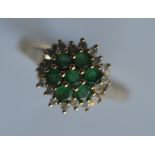 A small emerald and diamond circular cluster ring