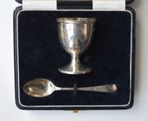 A boxed silver egg cup and spoon with reeded rim.
