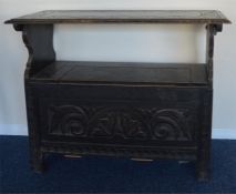 A small oak carved settle with hinged top and reed