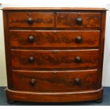A mahogany bow front chest of five drawers on ball