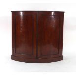 A 19th century mahogany bow fronted cabinet, the two doors enclosing shelves, on a plinth base, w.