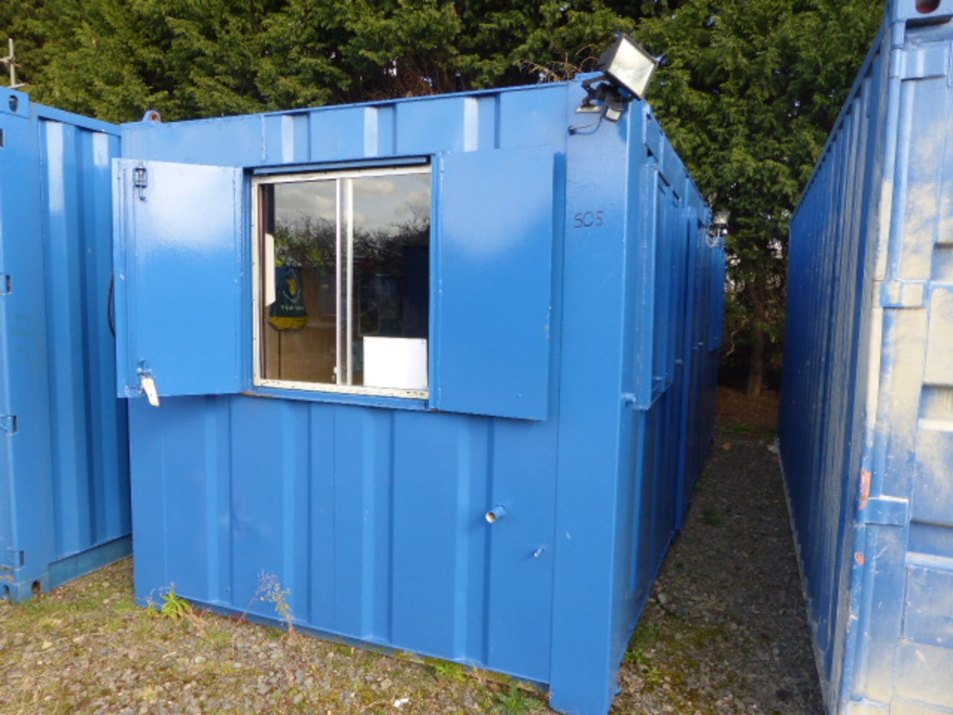 Corrugated steel clad office container building with security shutters and single door, exterior