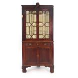 A George III and later oak two section corner cupboard surmounted by an Arabic head,