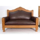 A Scandinavian oak framed and brown leather upholstered two seater sofa on scrolled feet