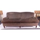 An overstuffed four seater sofa on six mahogany square tapering legs,