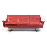 A Skippers Mobler red leather and button upholstered three seater sofa on an aluminium ski-type