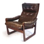 A 1970's stained beech and brown button upholstered adjustable reclining armchair on a sleigh-type