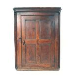 A late 17th/early 18th century oak panelled corner cupboard, the door enclosing three shelves, w.