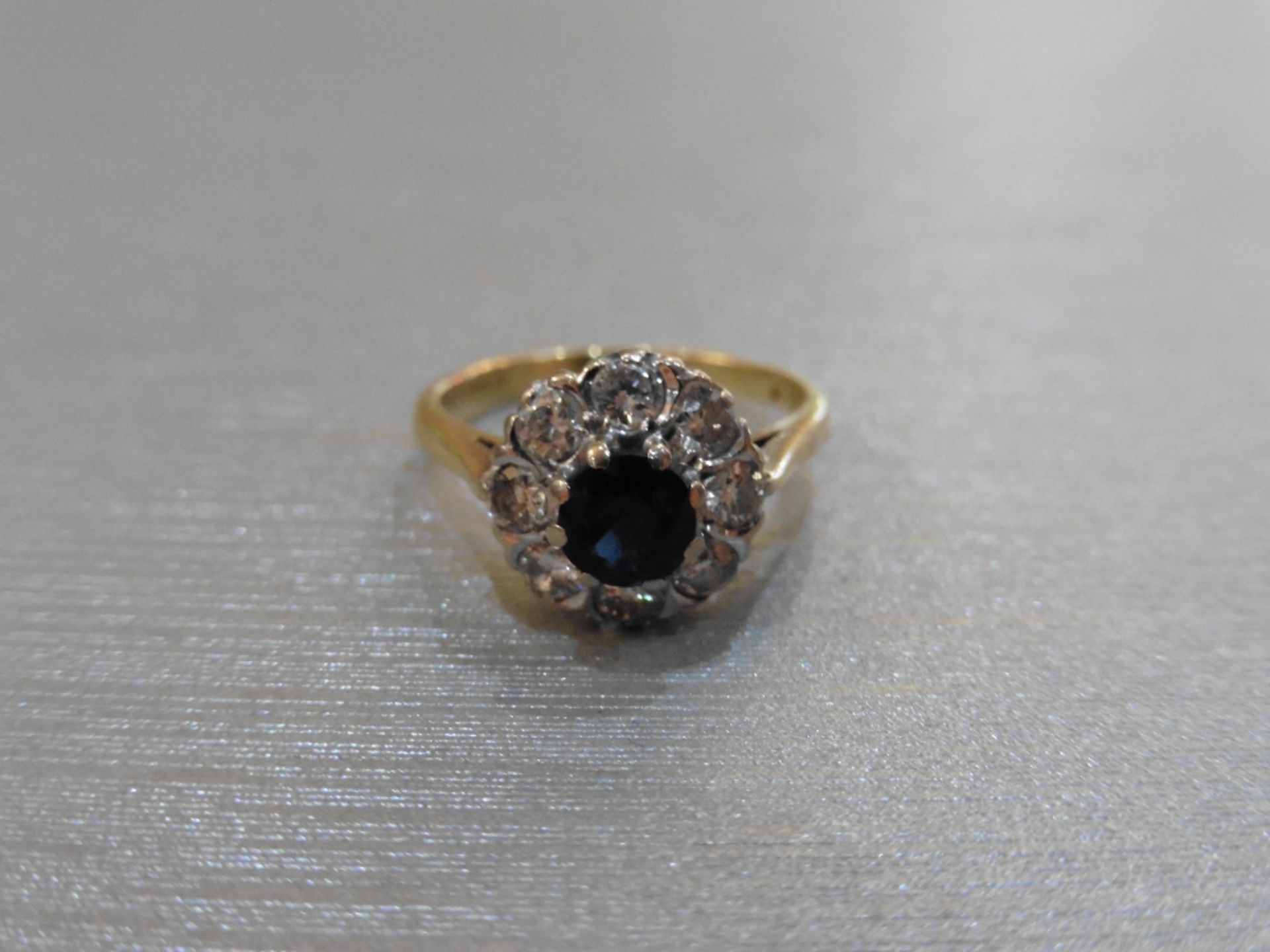 Pre-owned 18ct gold sapphire and diamond cluster ring set with a round sapphire measuring