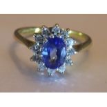 An 18ct gold sapphire and diamond cluster ring. Size L - The oval-shape sapphire, within a