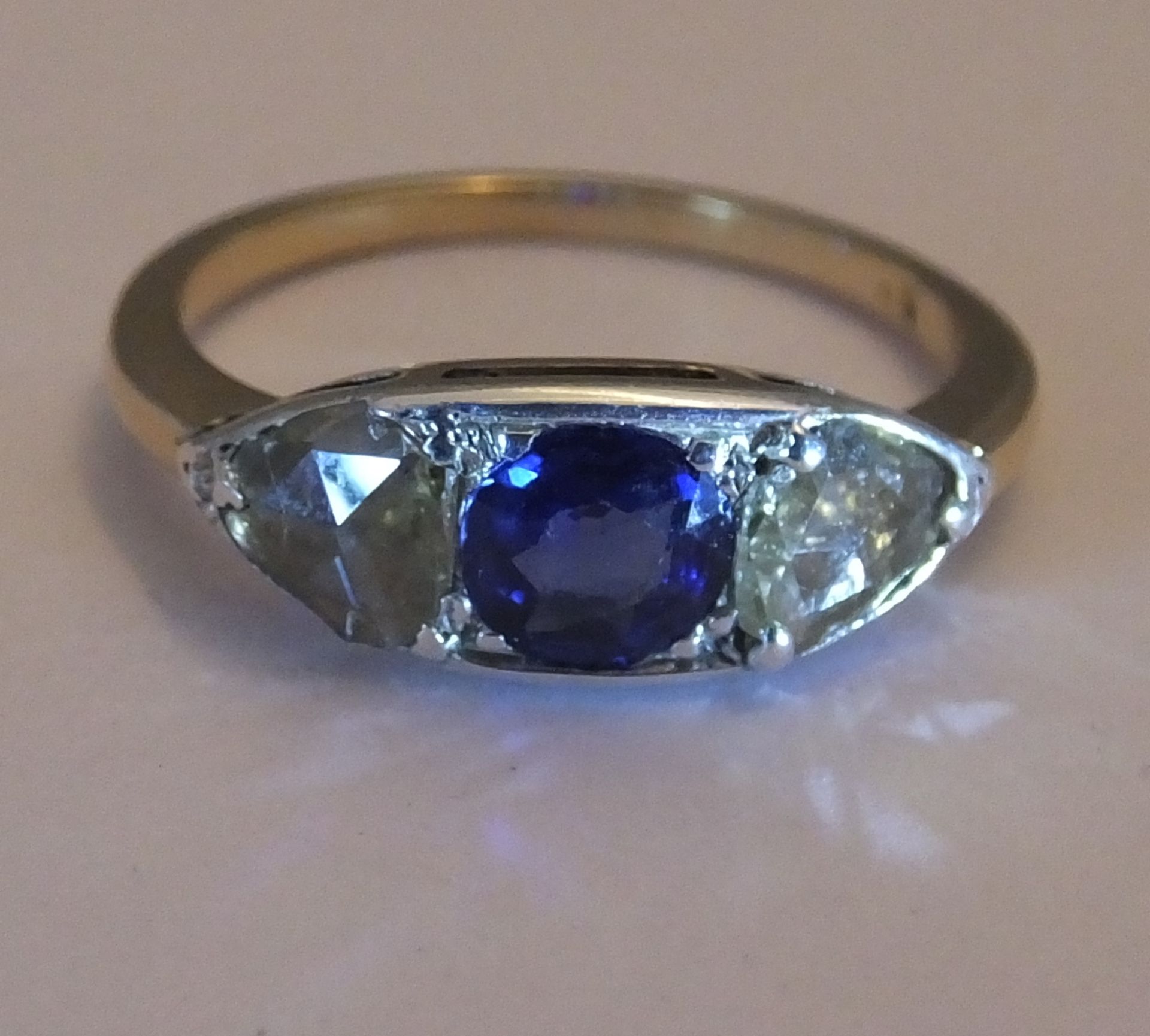 A sapphire and diamond three-stone ring. Size L - The circular-shape sapphire, with triangular-shape